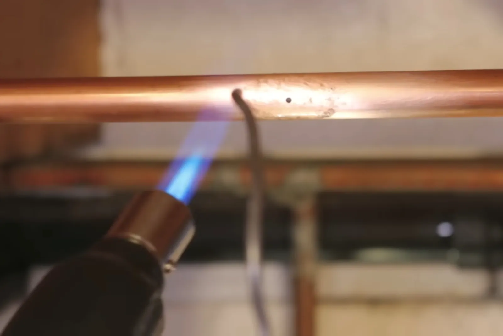 Torch soldering a replacement section of copper pipe after a burst