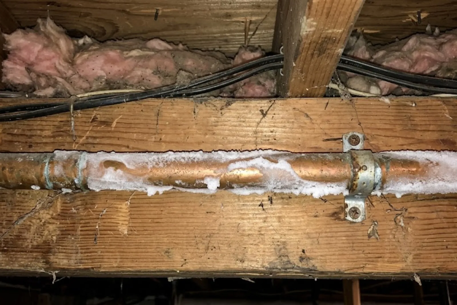 Frost covering a copper supply pipe between floor joists