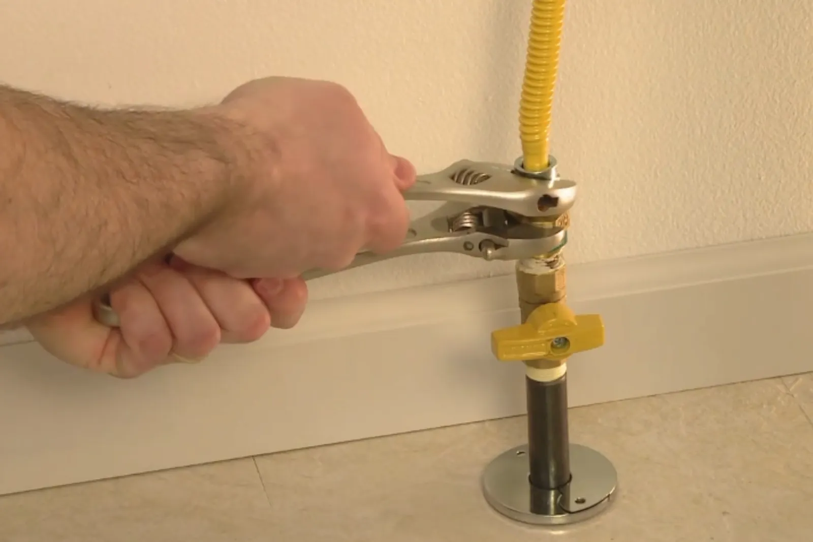 Tightening a yellow-handled gas shutoff valve on an appliance line