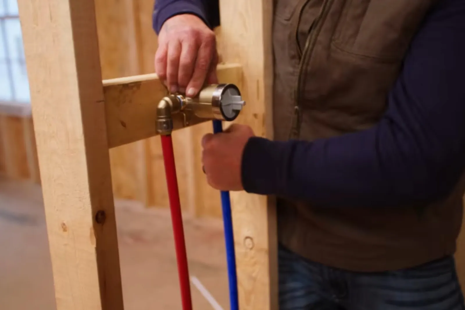 Plumber installing a shower valve with PEX supply lines in an open wall