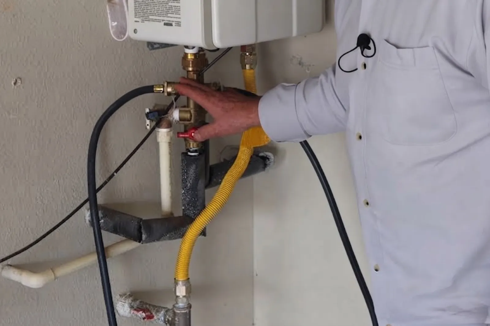 Plumber servicing the connections on a wall-mounted tankless water heater